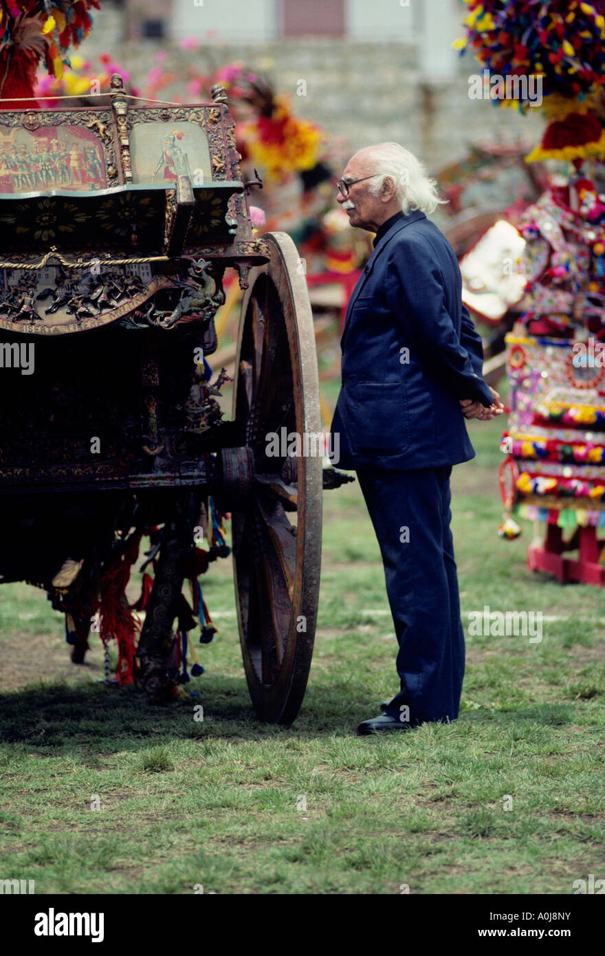 Eine sizilianische elder inspiziert eine kunstvolle handgefertigte und bemalte Eselskarren. Stockfoto
