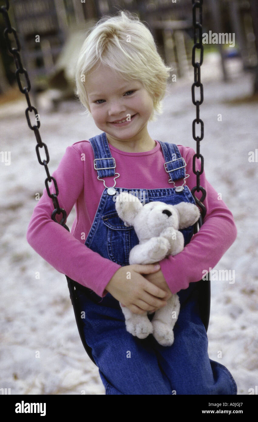 Porträt eines Mädchens sitzen auf einer Schaukel hält einen Teddybär Stockfoto