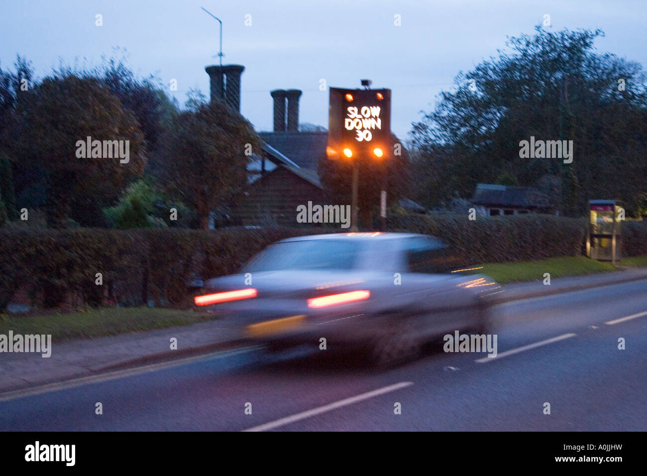 eine blinkende Geschwindigkeit Warnzeichen und Verkehr durch das Dorf zu beschleunigen Stockfoto