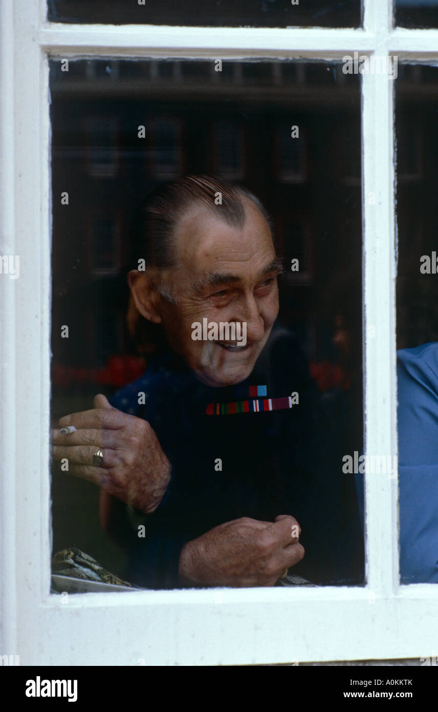 Pensionär Chelsea Uhren die Founders Day Parade aus einem Fenster im Royal Hospital, Chelsea, London, UK Stockfoto