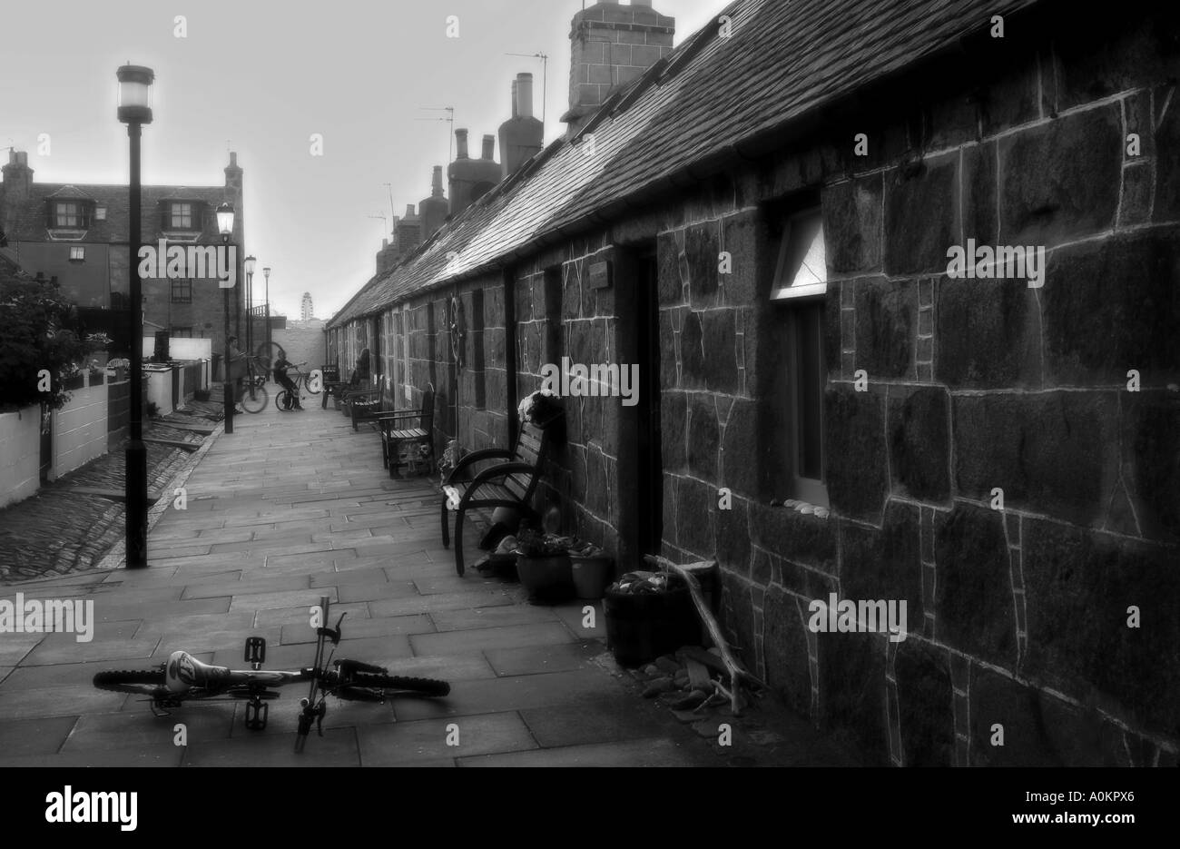 Ein zeitloses schwarz / weiß Bild Fittie, Aberdeen, einem alten Fischerdorf mit Kindern spielen und Fahrrad im Vordergrund Stockfoto