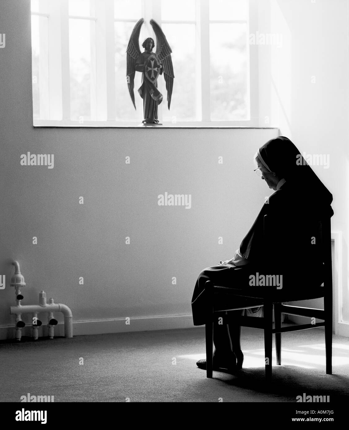 Nonne auf Stuhl im Gebet. Stockfoto