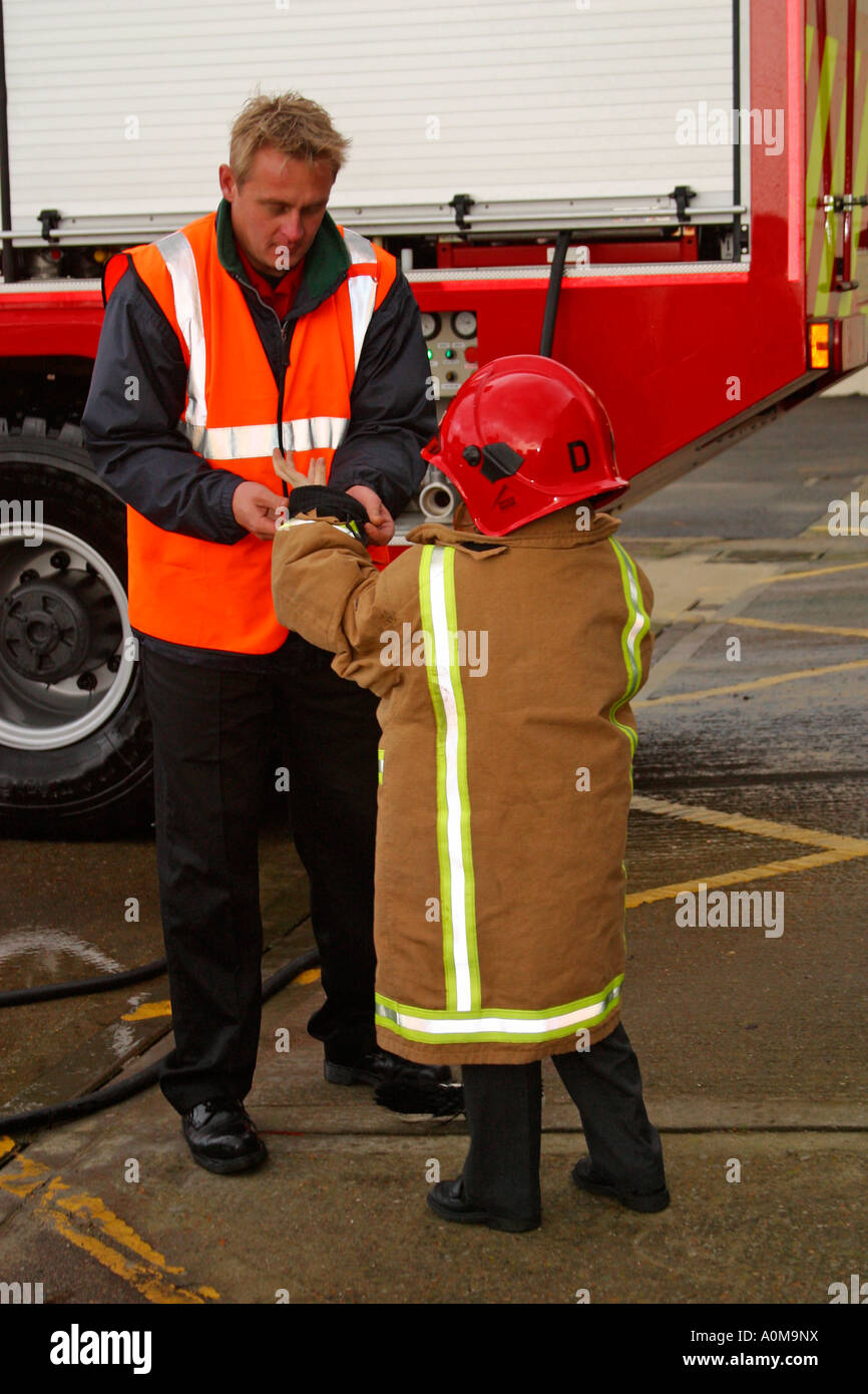 Kleiner Junge mit Firemans Jacke auf geholfen Stockfoto