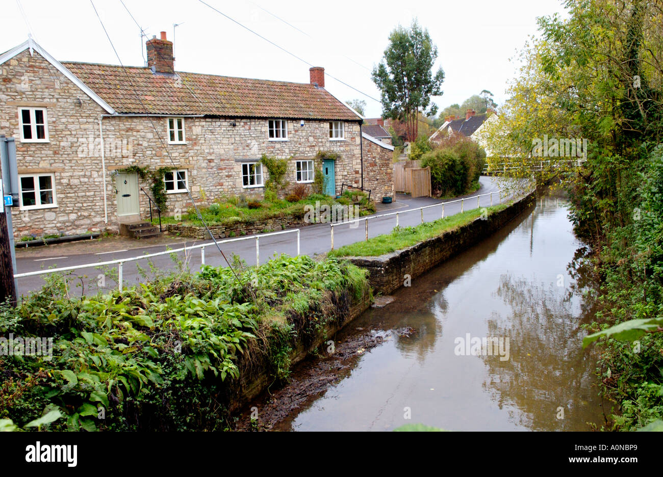 Reihe von Landhäusern neben langsam bewegenden Fluss im Dorf von Chew Magna in der Nähe von Bristol England UK Stockfoto