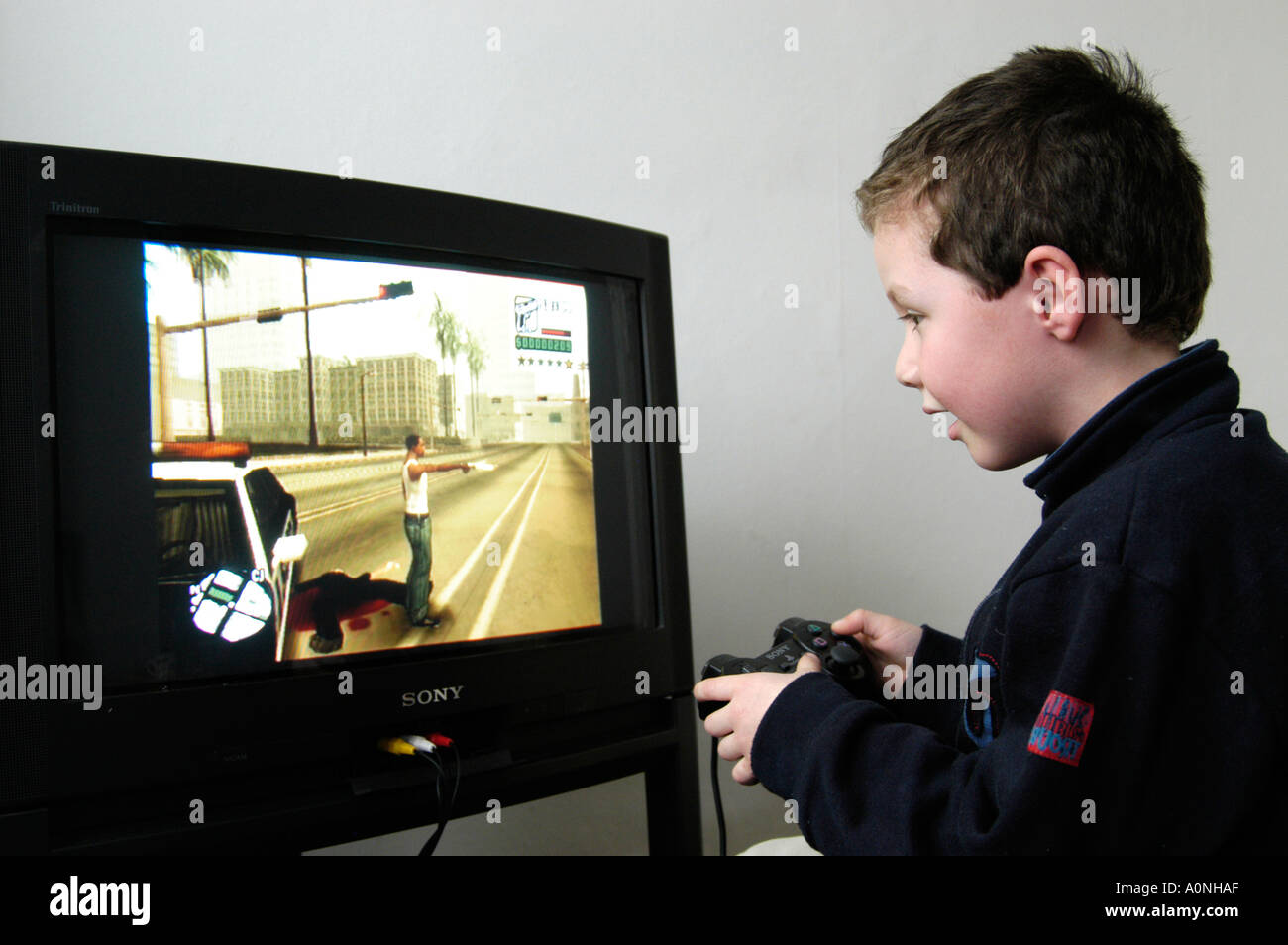 Kleine Jungen spielen gewalttätige 18 Zertifikat bewertet Computerspiel Grand Theft Auto auf Sony Playstation Konsole, England, UK Stockfoto