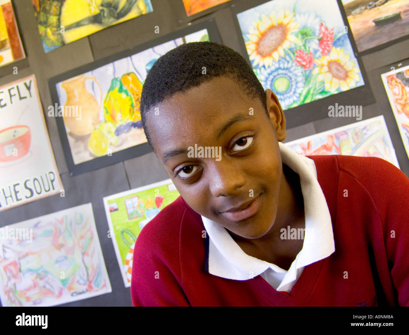 Schuljunge Portait eines selbstbewussten 13-15-jährigen schwarzen Jungen im Teenageralter im Klassenzimmer mit seinen Gemälden im Hintergrund Stockfoto
