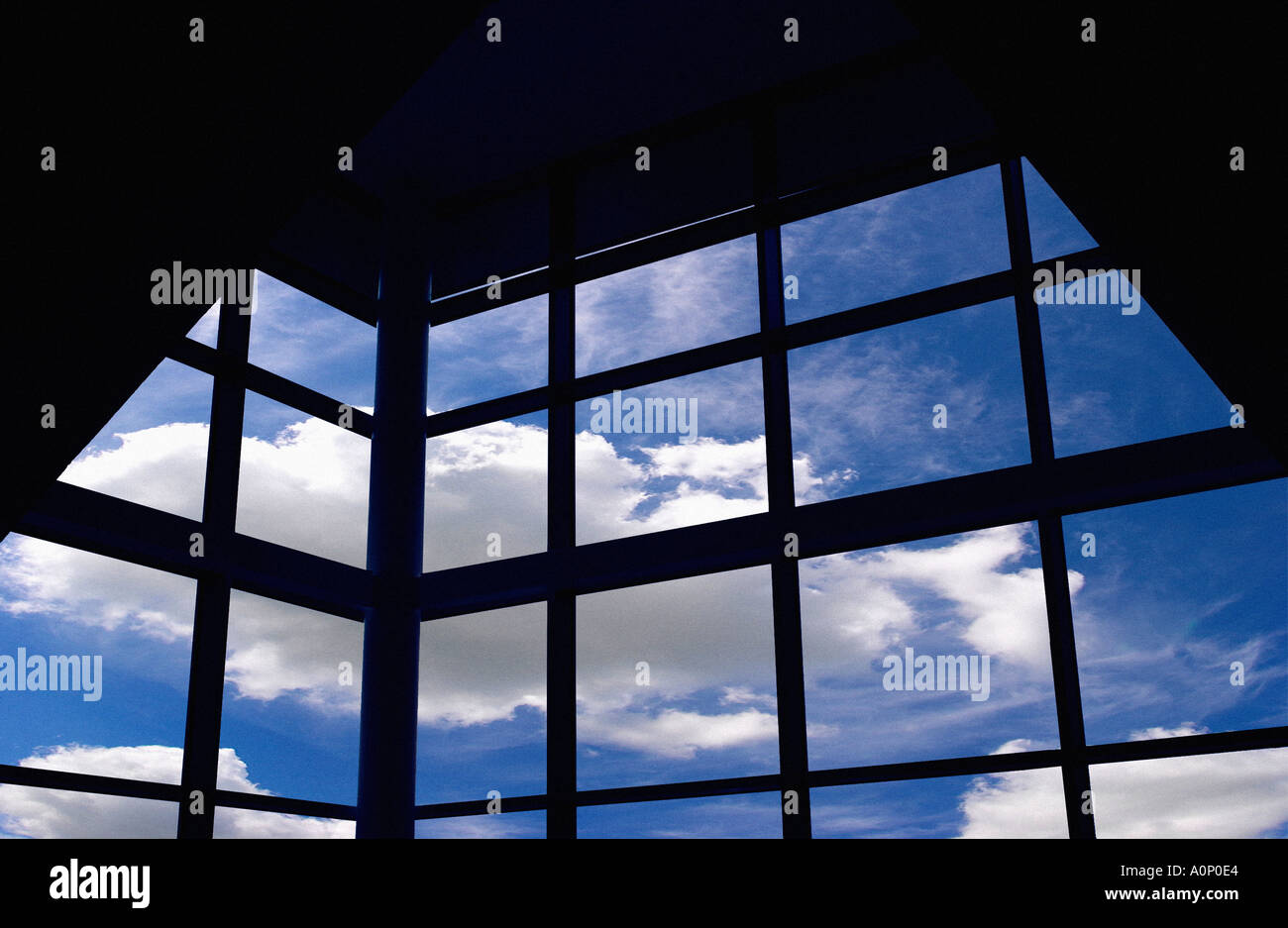 Blauer Himmel und Wolken durch Gitterfenster des modernen Gebäudes gesehen Stockfoto