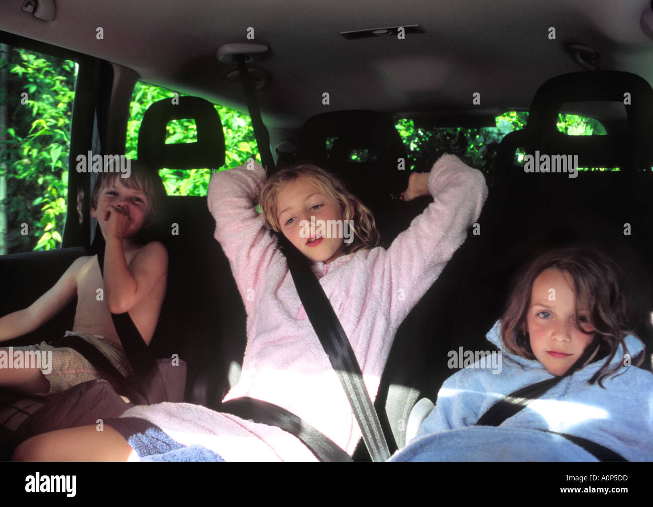 drei Kinder im Auto mit Sicherheitsgurt auf sitzen und auf der Suche müde und gelangweilt Stockfoto