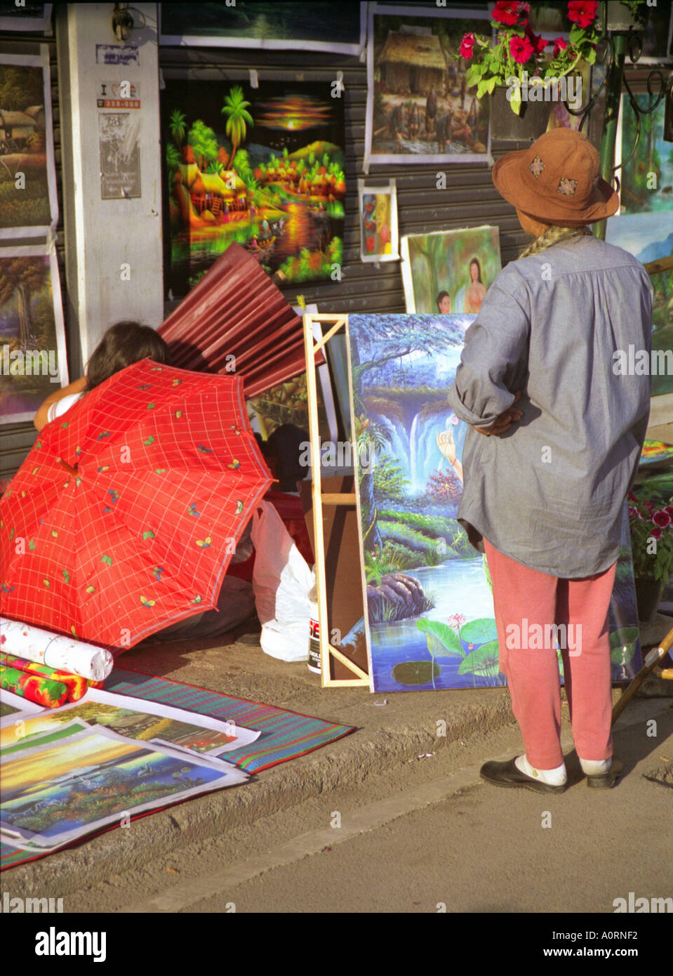 Streetart-Künstler Frau Display farbenfrohen Gemälden im Freien in belebten Gehweg Anusan Markt Chiang Mai Thailand Südostasien Stockfoto