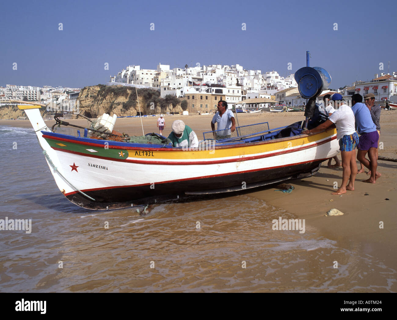 Albufeira Gruppe von Fischern Menschen am Ufer vorbereiten Starten Sie Fischerboot ins Meer an beliebten blauen Himmel Urlaub Strand Algarve Portugal Europa Stockfoto