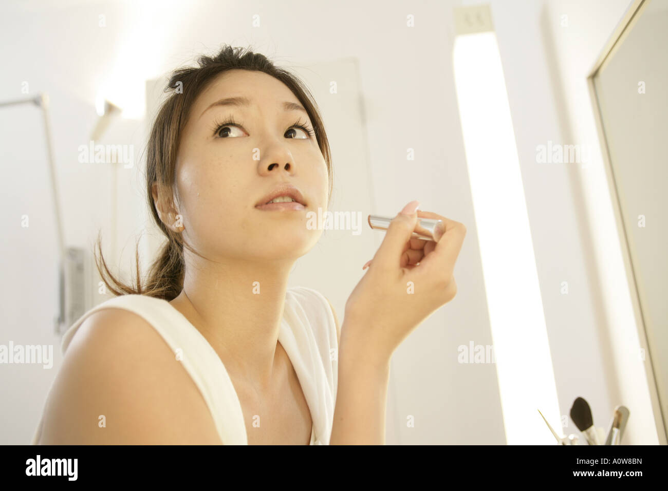 Nahaufnahme einer jungen Frau hält einen Lippenstift und seitwärts suchen Stockfoto
