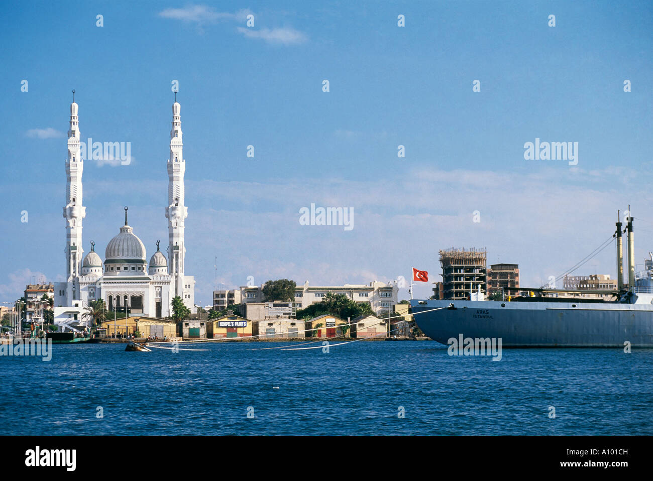 Eine gewölbte Moschee mit hohen Minaretten und ein großes Schiff vor der Küste am Eingang bis zum nördlichen Ende des Suez-Kanals in Port Said gefesselt Stockfoto
