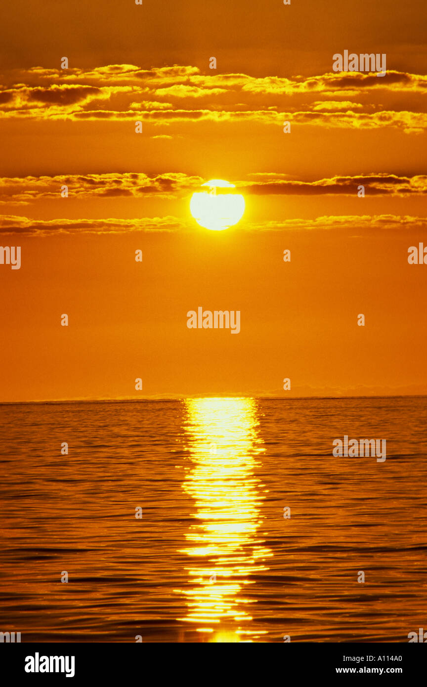 AUFGEHENDEN SONNE VERWANDELT HIMMEL UND WOLKEN IN DEN GLEICHEN GOLDENEN FARBE WIE DAS MEER Stockfoto