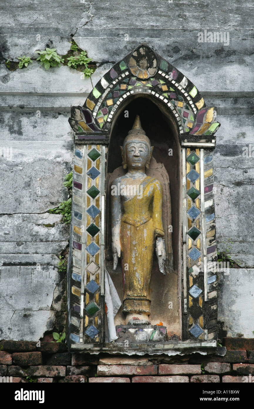 Buddha in gelben Roben in einer Nische eingelegt mit farbigem Glas oder Semi Edelsteine sehr hell und bunt, wenn Wat Luang Tempel in Phrae zum ersten Mal im 13. Jahrhundert festgelegt gewesen wäre Stockfoto