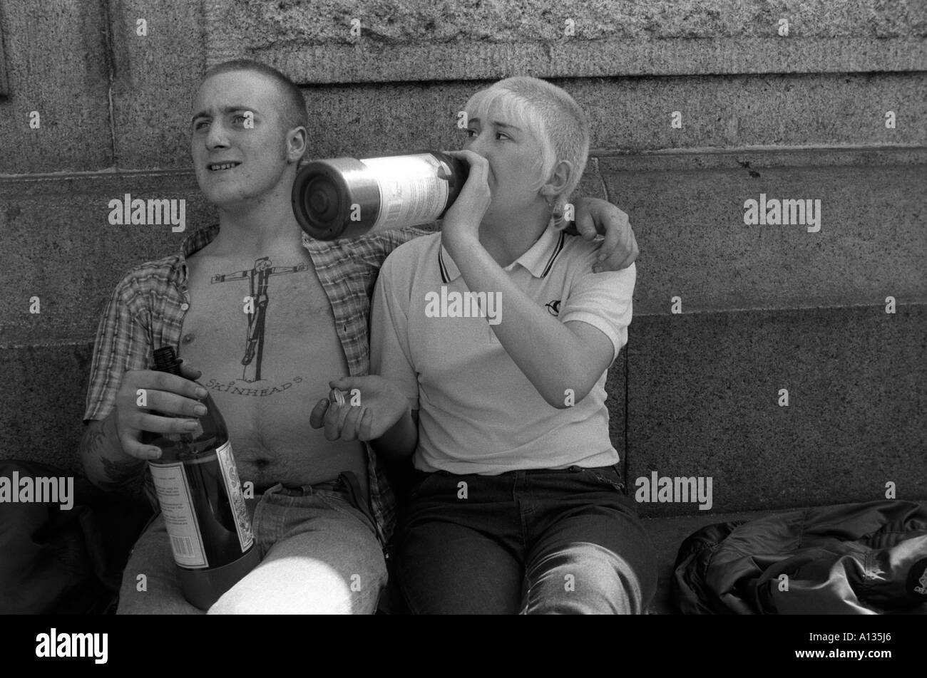 Skinheads ein Paar, das Alkohol aus einer Flasche trinkt der Mann Hat ein Tattoo von Christus als Skinhead gekreuzigt auf Seine Brust London UK 1982 HOMER SYKES Stockfoto