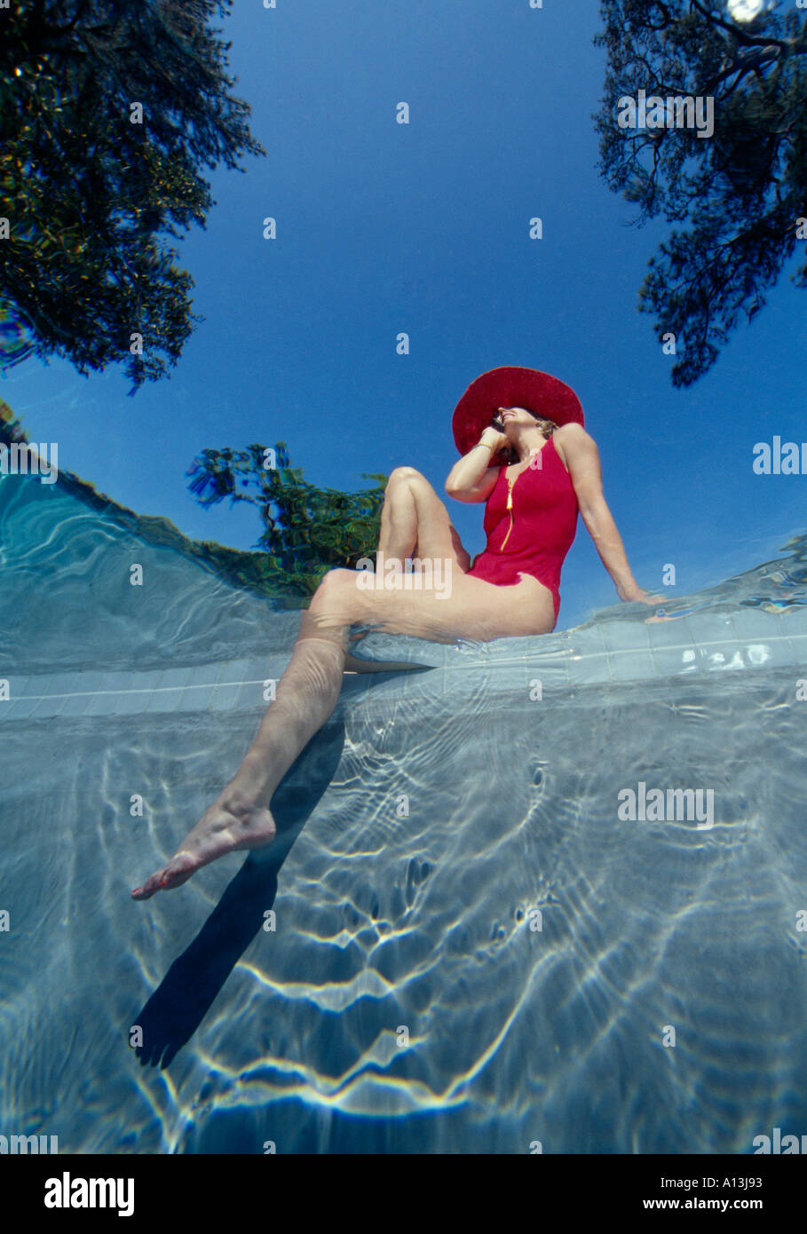 Frau im roten Badeanzug und schwarzen Hut mit Beinen im Wasser, das aus Unterwasser Stockfoto
