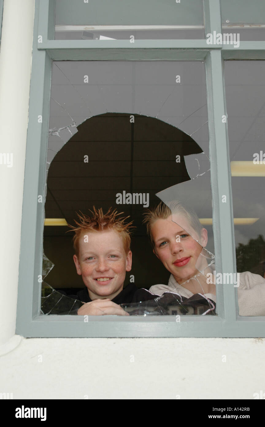 zwei Schuljungen verschmitzt durch zerbrochene Fenster suchen Stockfoto