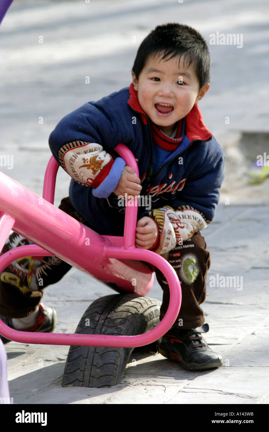 Chinesischen Jungen glücklich zu spielen auf einem Teeter Todder, Dongdan Park, Peking, China. Stockfoto