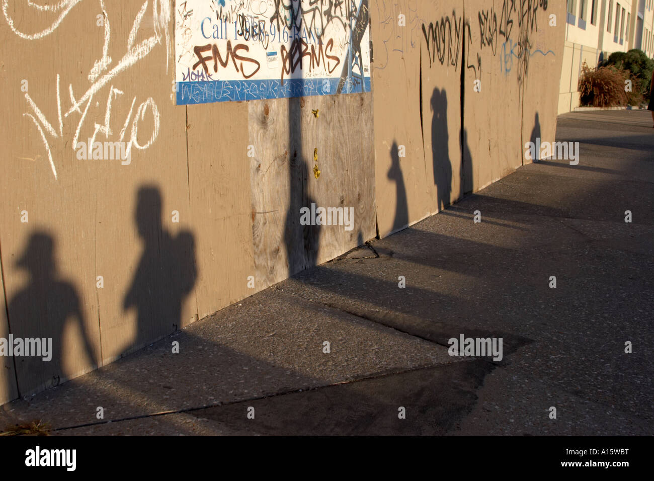 Schatten der Menschen gegen eine Wand Graffitied auf einen Strandspaziergang. Stockfoto