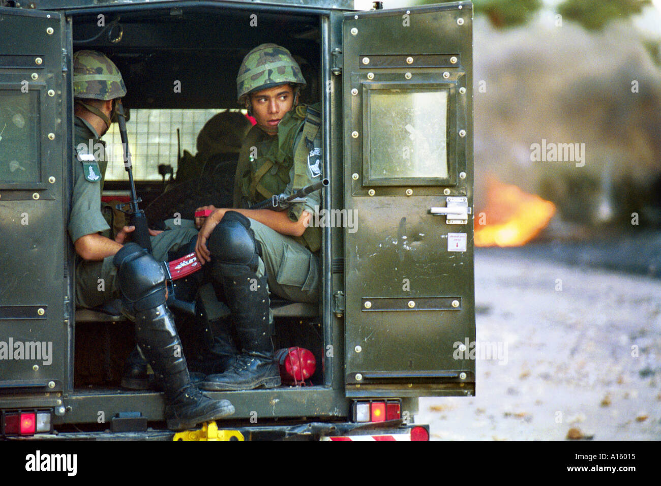 Israelische Soldaten sitzen in ihrem gepanzerten Fahrzeug wie Palästinenser in der Westbank-Stadt von Steinen und Molotow-Cocktails werfen Stockfoto