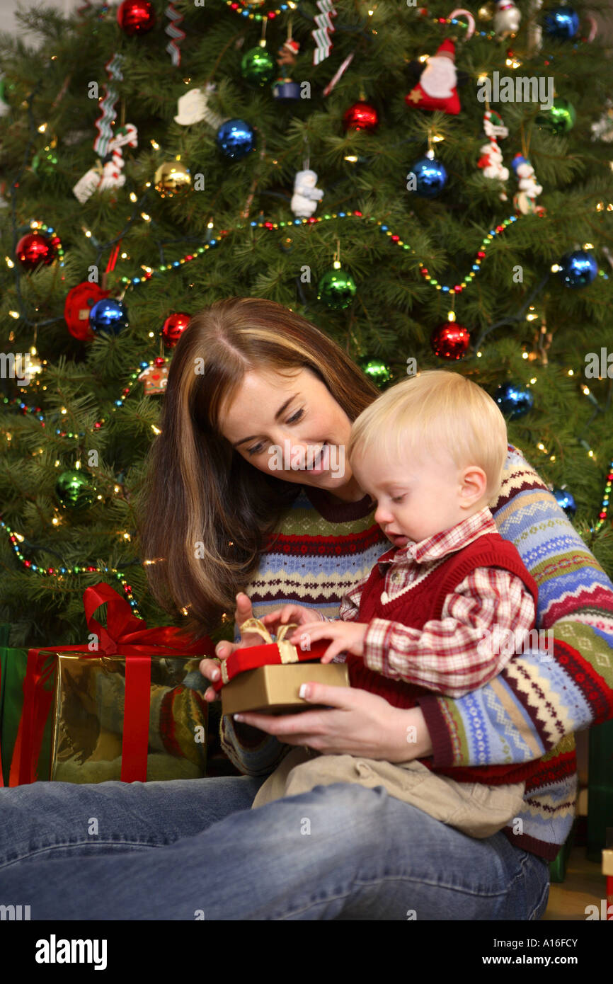 Eröffnung Weihnachtsgeschenk mit einjährigen Sohn Mutter Stockfoto