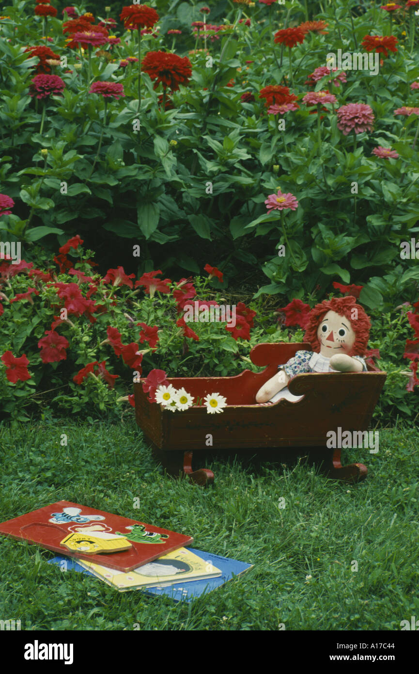 Nostalgie: Spielzeug im Garten - Raggedy Ann in eine antike Wiege und alten Holzpuzzle in bunten Home Garten, Missouri USA Stockfoto
