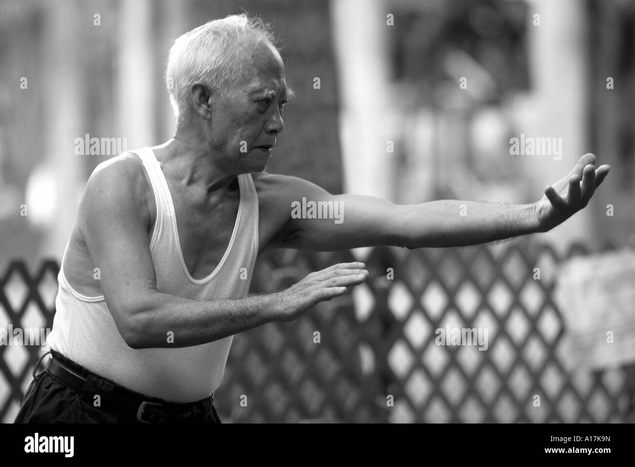 Ein älterer Mann praktiziert Tai Chi in einem Park in Hong Kong. Stockfoto