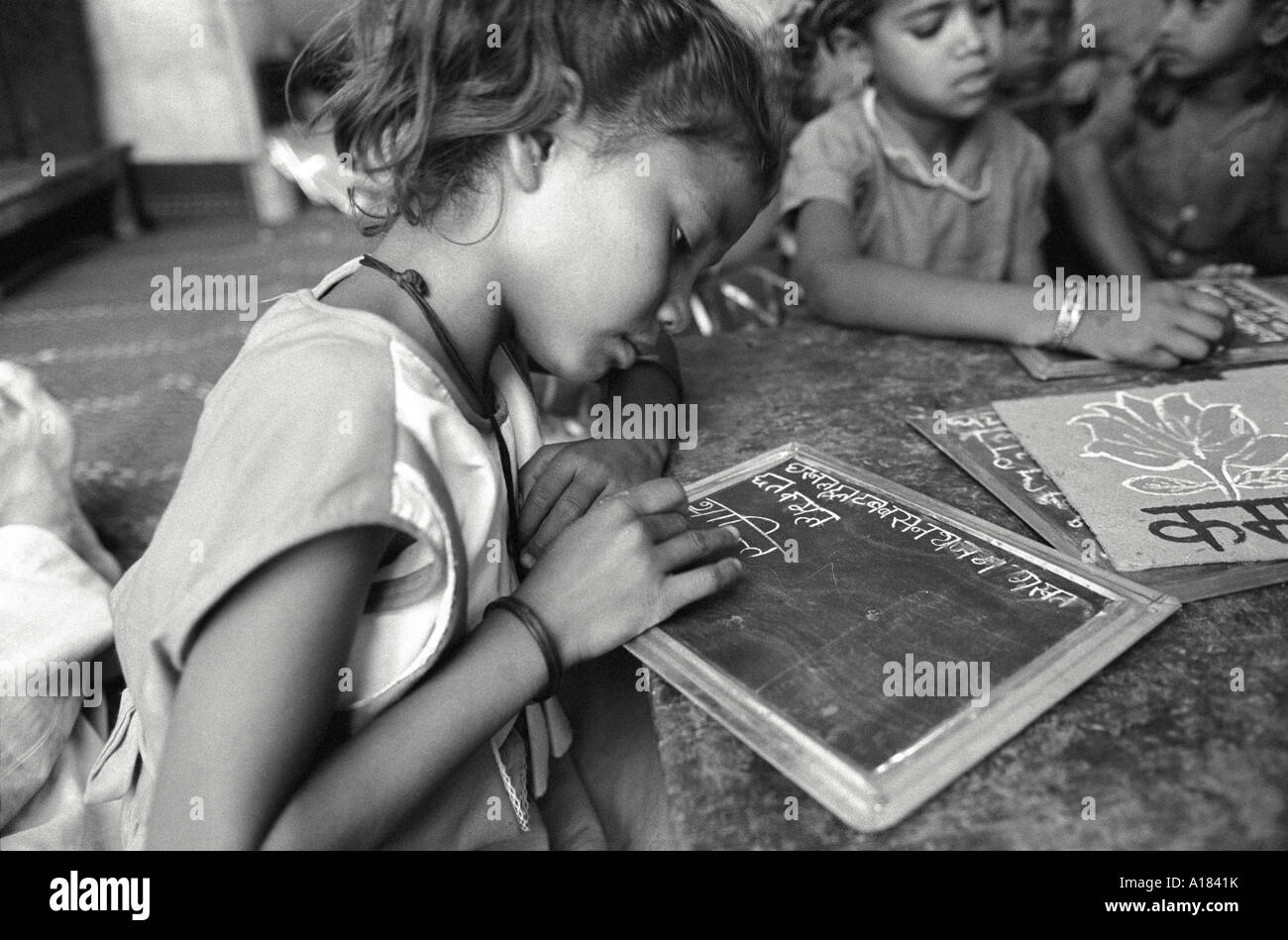 S/W von Kindern, die lernen, in einem Klassenzimmer in einer Schule für Straßenkinder in Kalkutta, Indien, auf Tafeln zu schreiben Stockfoto