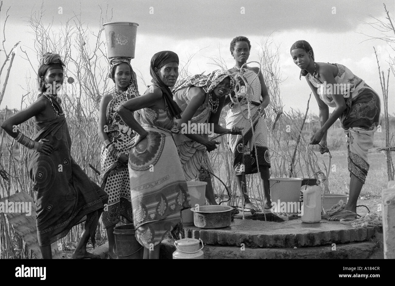 B/W von Oromo-Frauen in ländlichen Regionen in traditionellen Kleidungs, die Wasser auf einem Brunnen ziehen. Wajir, N.E. Kenia Stockfoto