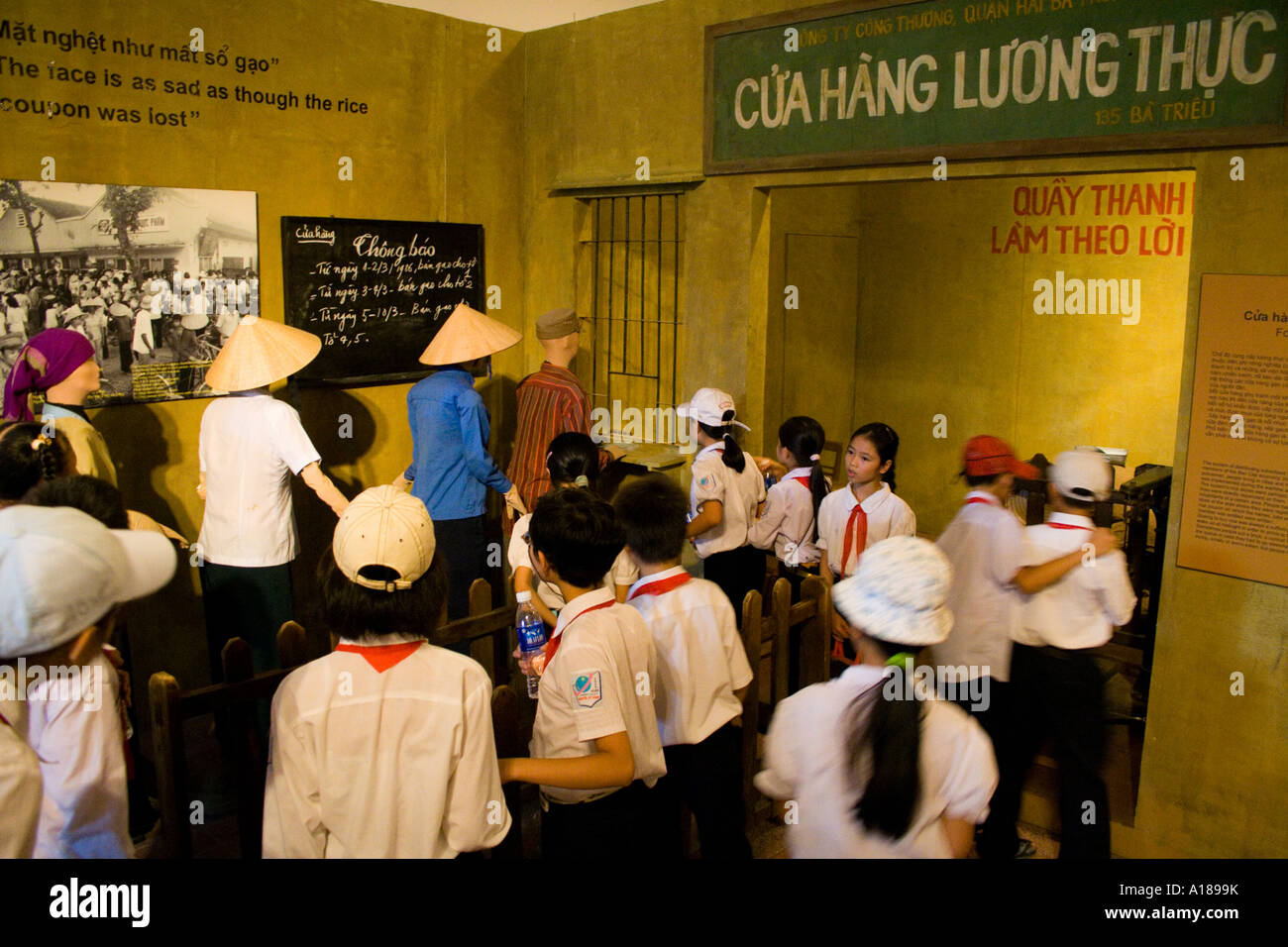 2007 Foto Bild uniformierten Schulkinder Spaziergang durch eine Anzeige auf Ration Karte Linien in frühen Tagen der Kommunismus von Vietnam Stockfoto