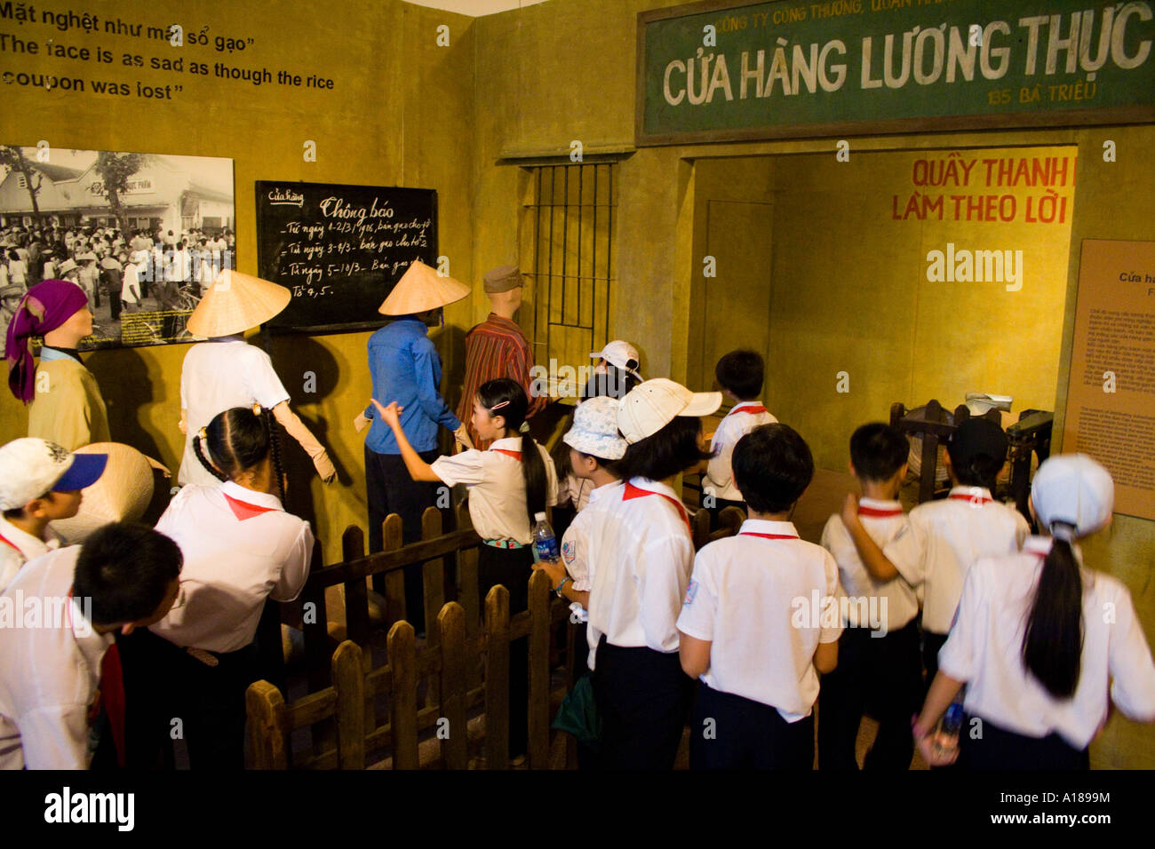 2007 uniformierten Schülerinnen und Schüler gehen über ein Display im Ration Karte Linien in frühen Tagen der Kommunismus von Vietnam Stockfoto