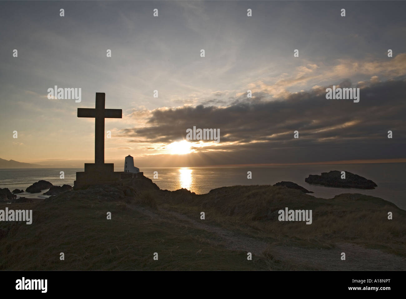 LLANDDWYN Insel ISLE OF ANGLESEY NORTH WALES UK Dezember geht die Sonne hinter großen steinernen Kreuz und Twr Mawr Stockfoto
