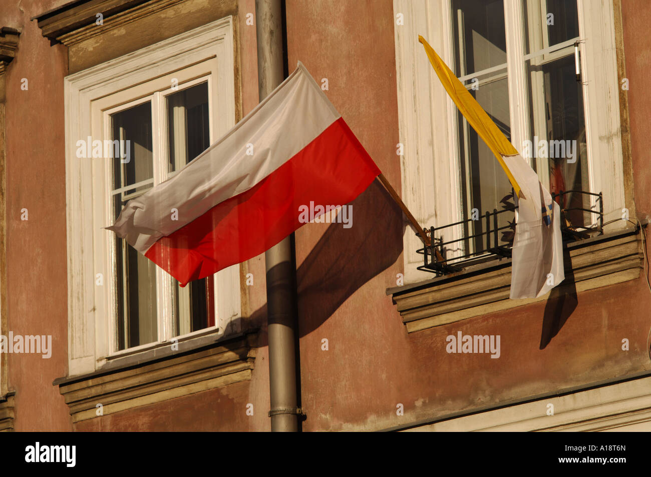 Eine polnische Nationalflagge und gelbe katholische religiöse Flagge hängen vor ein Fenster der Wohnung im Zentrum von Krakau Stockfoto