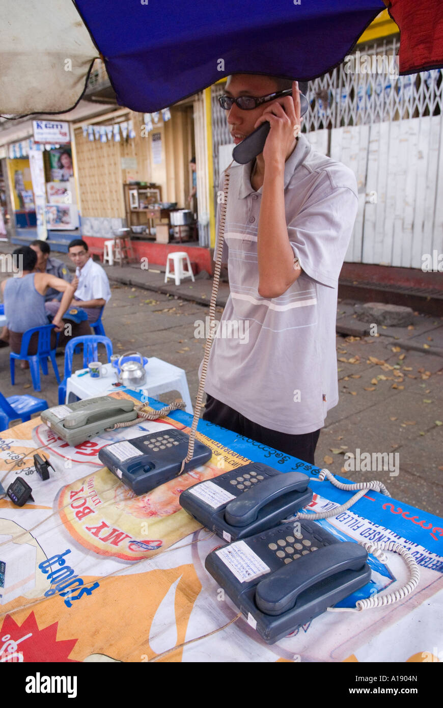 Junger Mann machen Anruf von Straßenhändler Yangon Myanmar Stockfoto