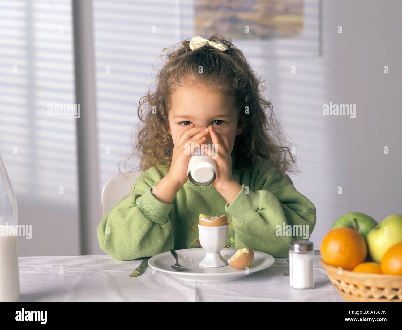 Kleines Mädchen ist ein Glas Milch trinken. Stockfoto