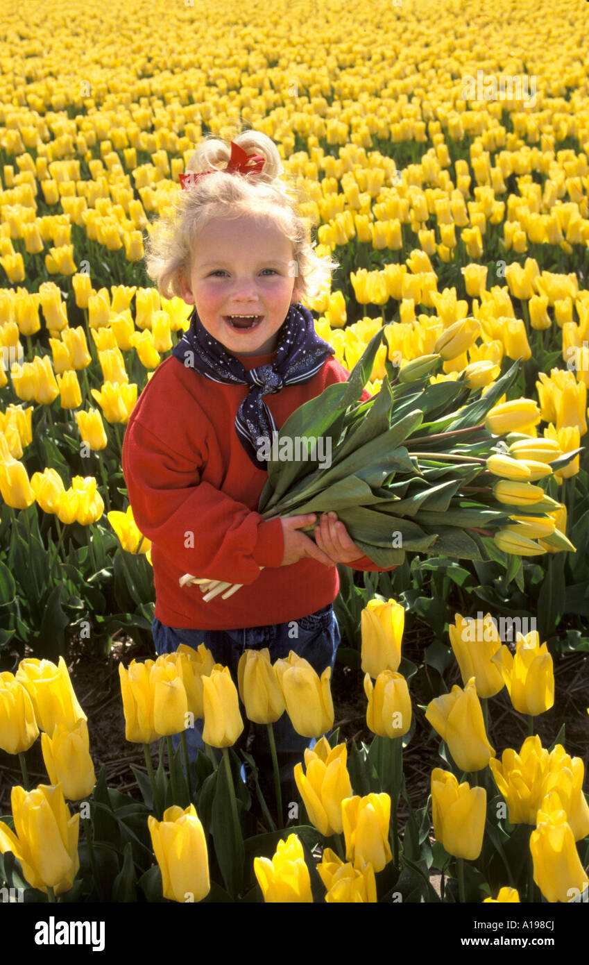 Kleines blondes Mädchen stehend in ein Blumenbeet Stockfoto