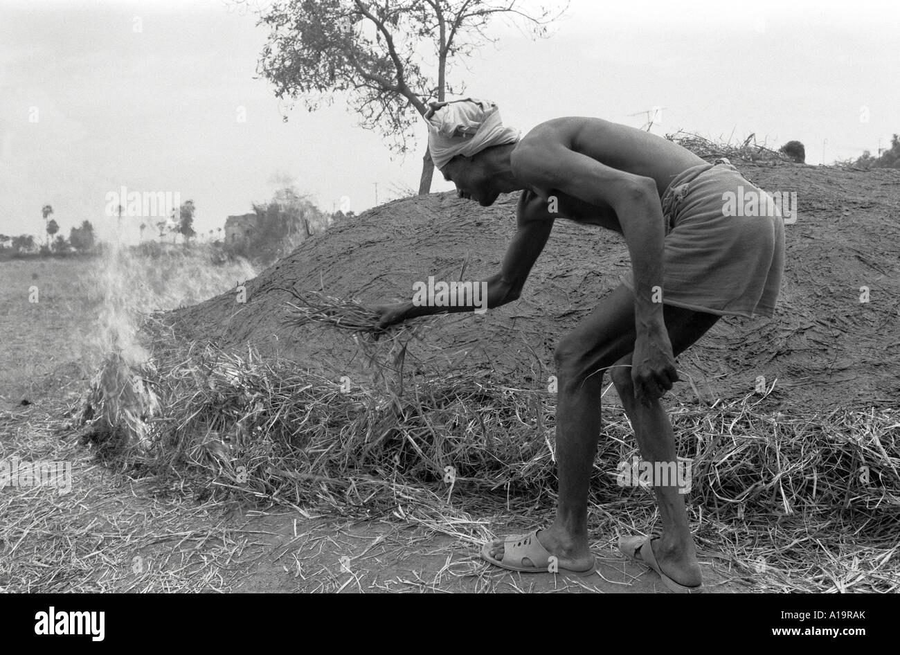 S/W eines Töpferarbeiters, der einen primitiven, traditionellen Ofen im ländlichen Tamil Nadu, Südindien, beleuchtet Stockfoto