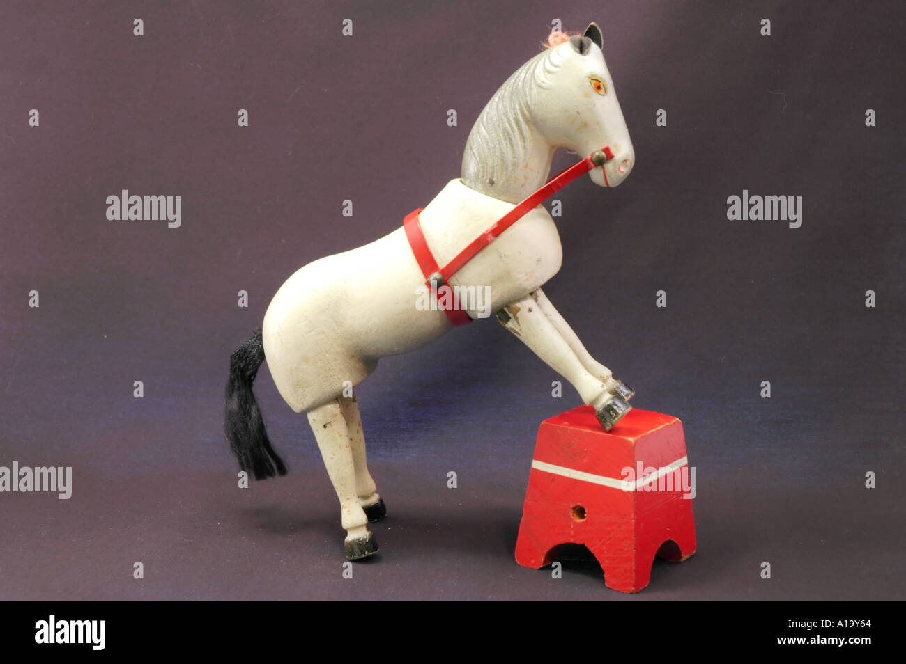 Antikes Holz Zirkus Spielzeug weißes Pferd stehend mit seinen vorderen Hufen auf einem Hocker Stockfoto