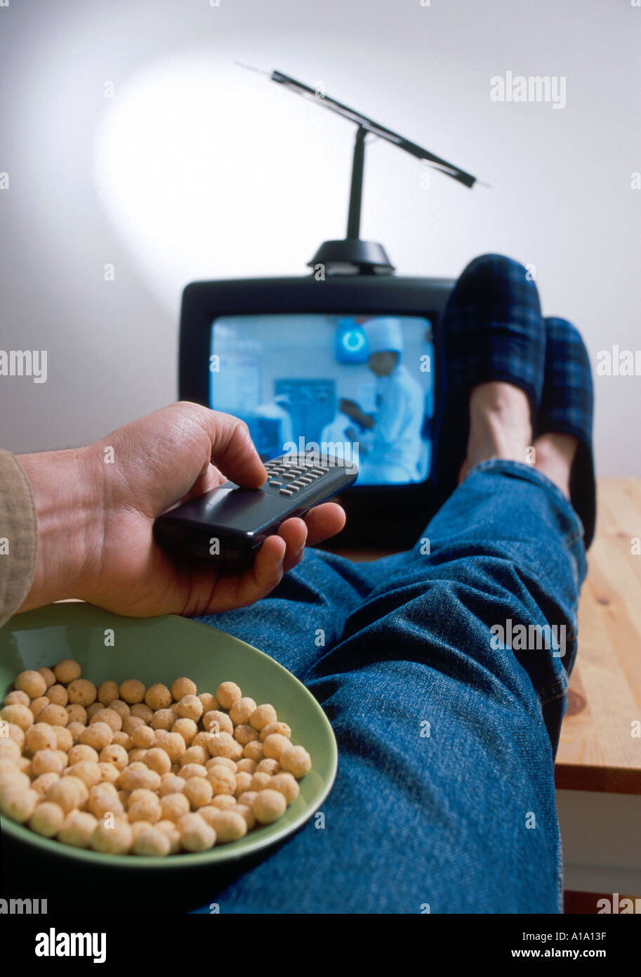 Bachelor Lebensstil - portable TV, Füße auf dem Tisch, Snacking auf Muttern Stockfoto