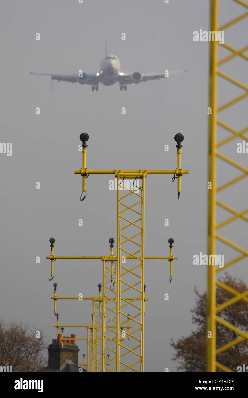 Flughafen-Start-und Landebahn-Ansatz Landescheinwerfer mit kommerziellen Verkehrsflugzeug vorbei über Schornstein auf dem Dach Stockfoto