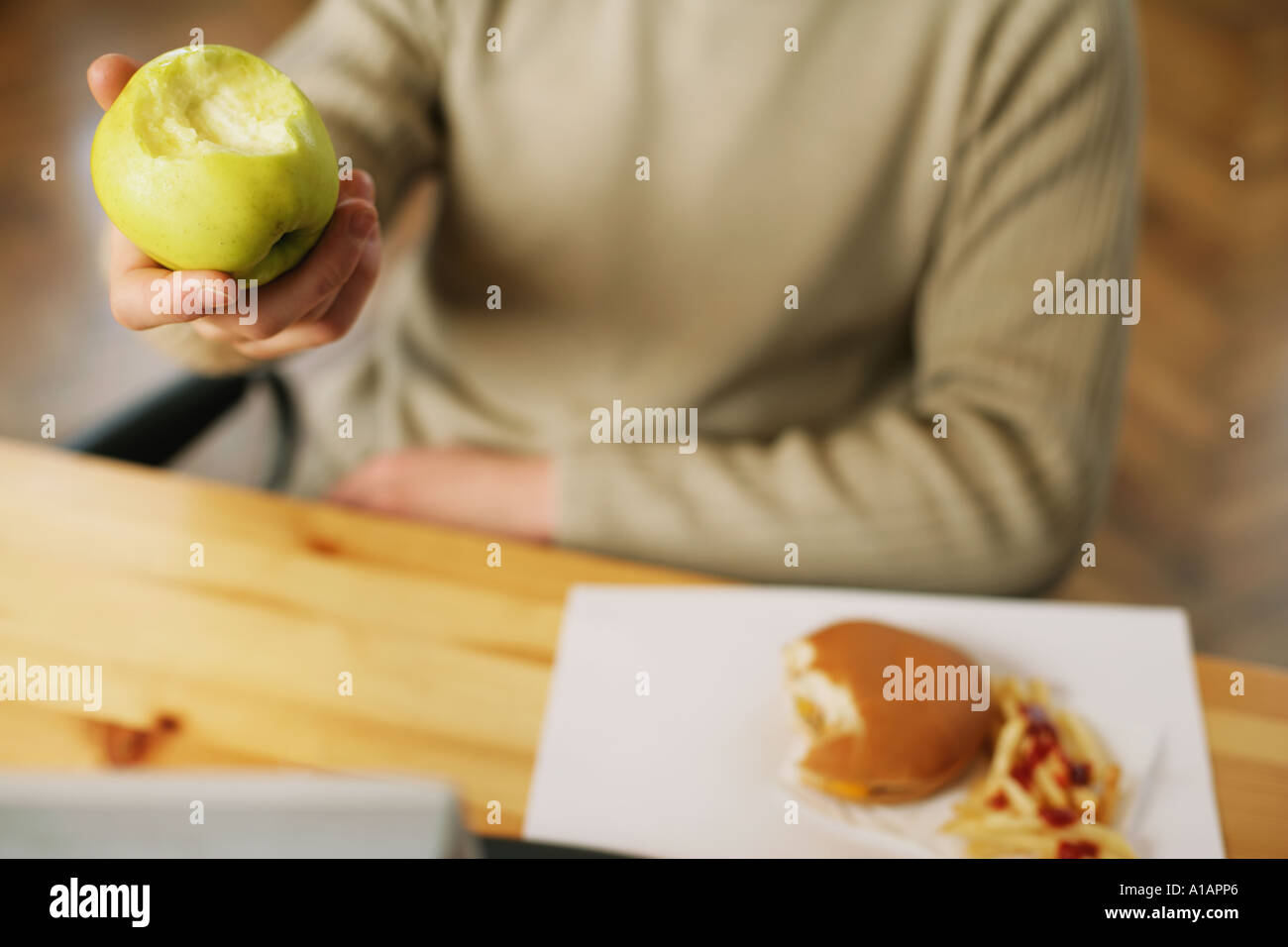 Mann mit einer halben Apfel und Cheeseburger gegessen Stockfoto