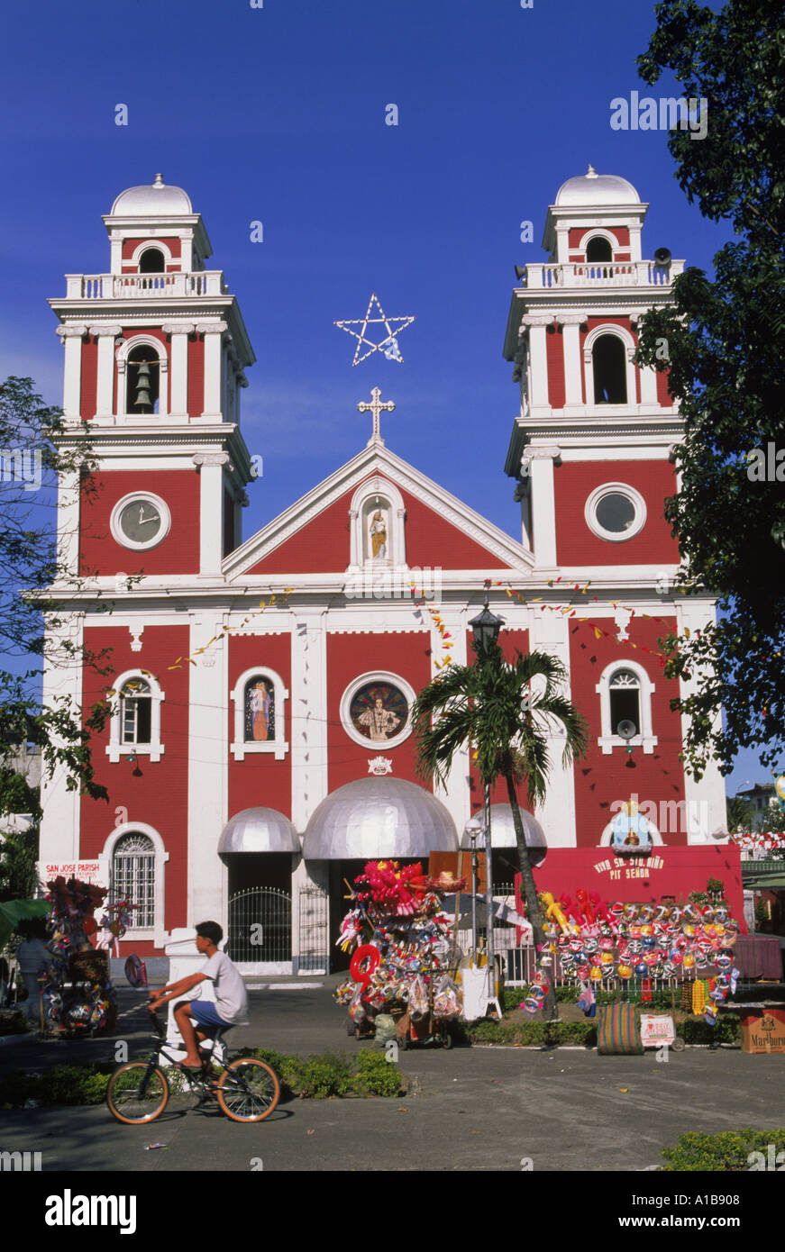 Junge auf Fahrrad und Stall zu verkaufen Spielzeug und Masken außerhalb San Jose Pfarrkirche in Iloilo City auf Panay Insel der Philippinen-A Stockfoto