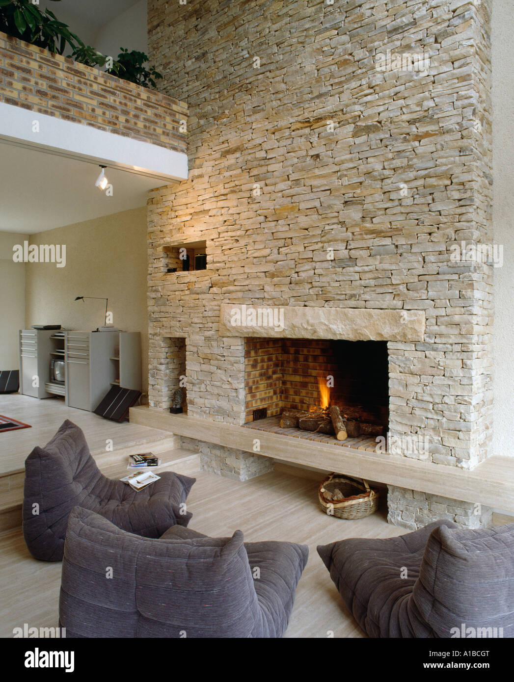 Brennenden Feuer im Kamin in Steinwand umgebaute Scheune, mit modernen  grauen Sessel Stockfotografie - Alamy