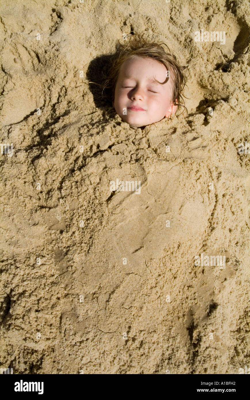 Kind spielt am vergraben im Sand am Strand Stockfoto