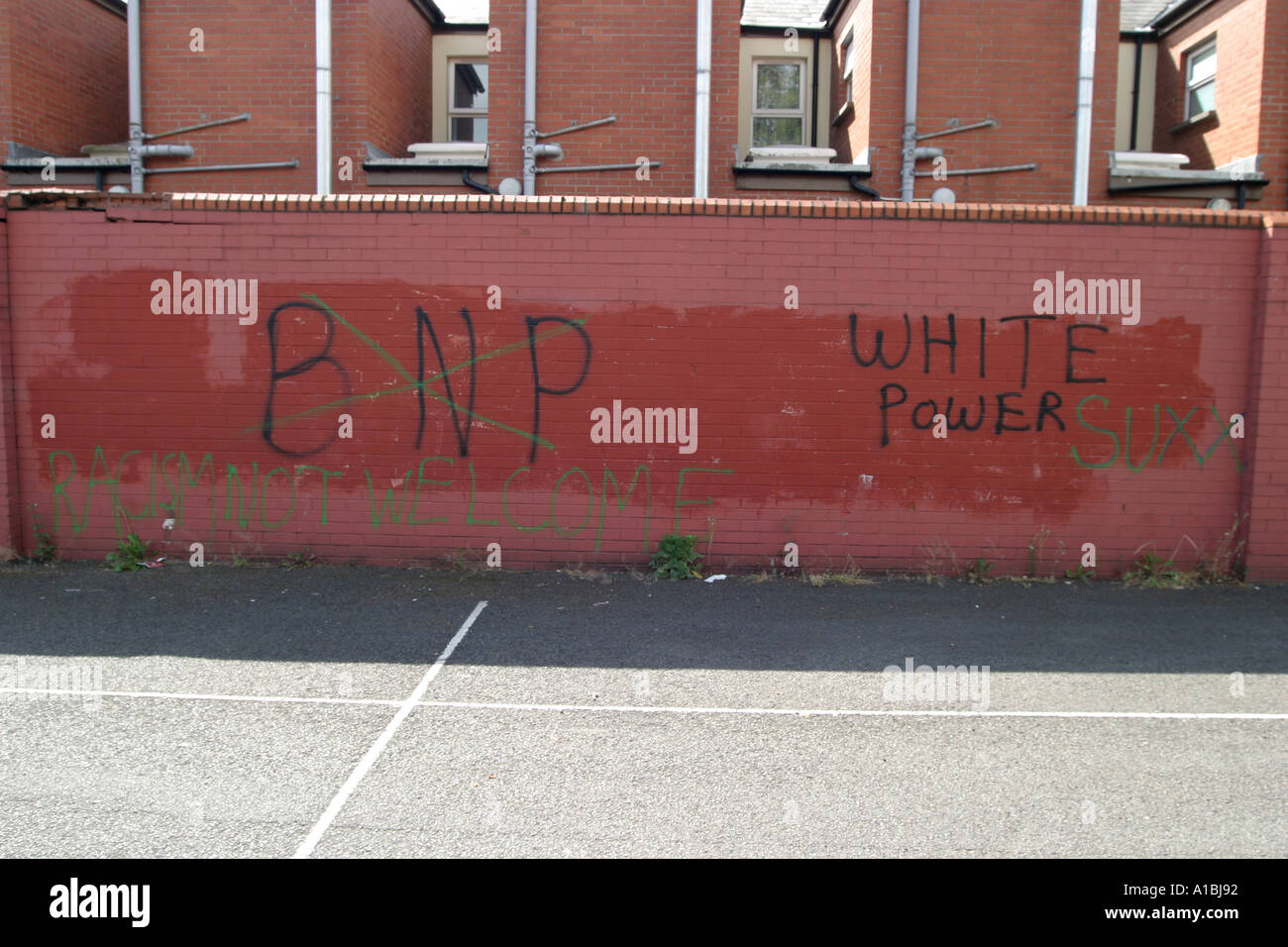 Rassistische und anti-rassistische Graffiti auf roten Backsteinmauer in Belfast, Northern Ireland Stockfoto