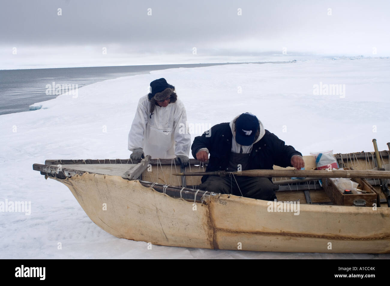 inupiatwalfänger mit einem Hautboot und Walfanggeräten am Rande eines Blei im gefrorenen Tschukchi-Meer Stockfoto