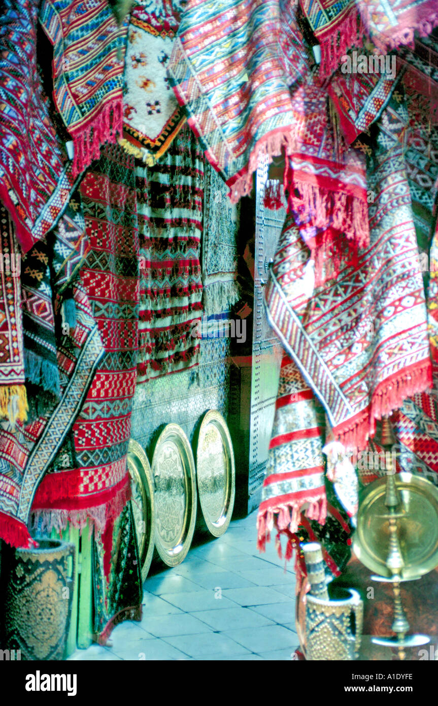 Afrika Marokko Tanger Kunsthandwerk zum Verkauf in winzigen Laden in alten Tanger Hand gefärbte Stoffe Teppiche Messingtabletts Stockfoto