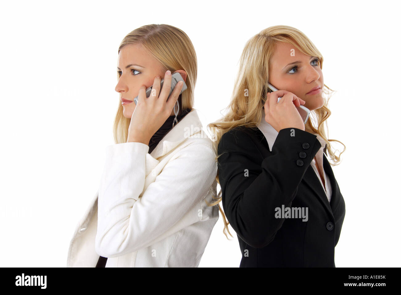 zwei jungen blonden Frau stehen Rücken an Rücken und telefonieren Stockfoto