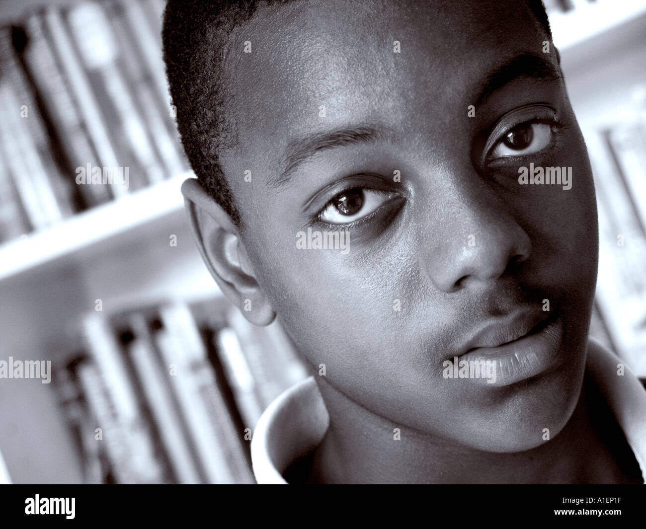 AFRIKANISCHER JUNGE STUDENT 13-15 Jahre Nahaufnahme fesselndes, kraftvolles Schwarz-Weiß-Porträt eines jungen schwarzen männlichen Schülers in der Schulbibliothek Stockfoto