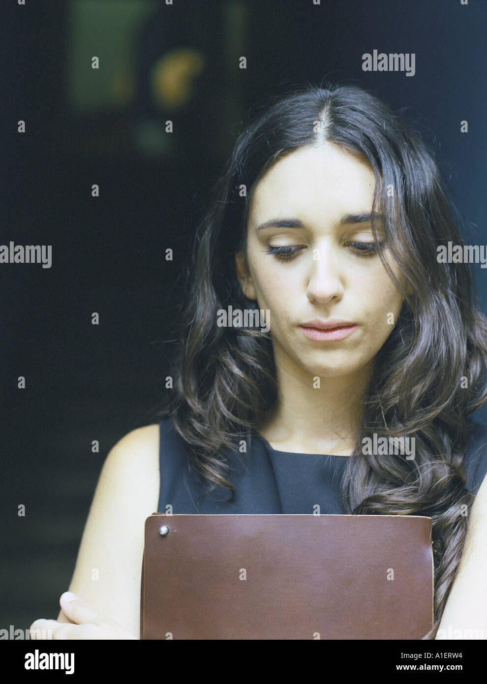 Frau hält Ordner vor der Brust, auf der Suche nach unten Stockfoto